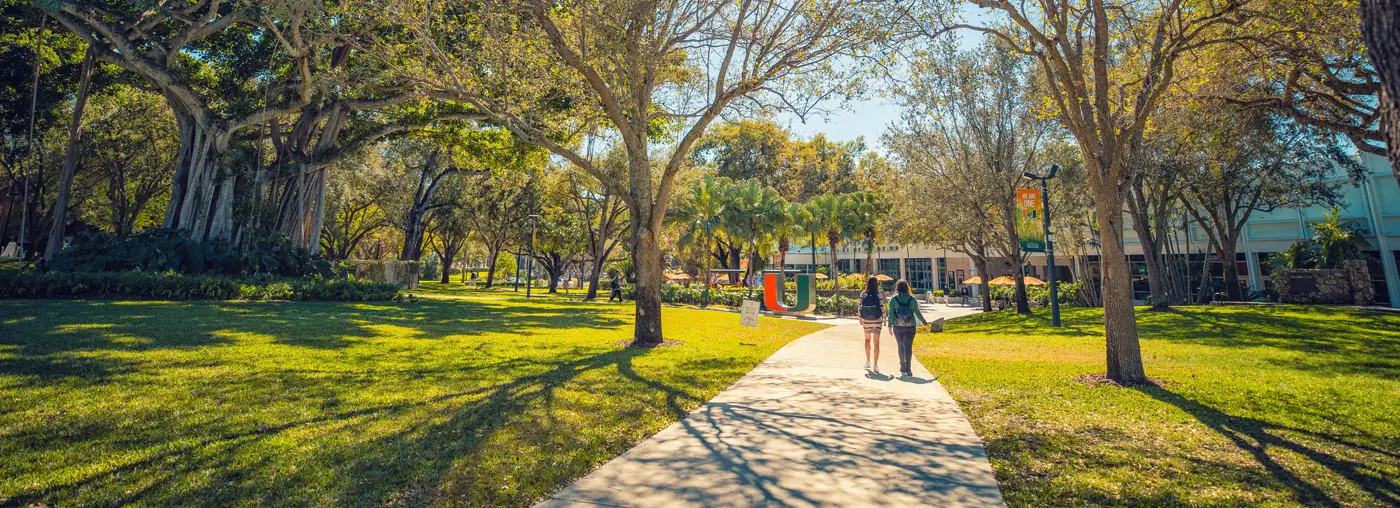 Two people walking on the sidewalk on campus